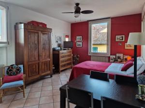 ボローニャにあるCa di Valeの赤い壁のベッドルーム1室、ベッド1台、デスクが備わります。