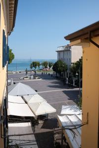 - un ensemble de parasols blancs assis sur une terrasse dans l'établissement APT centrale vista lago Incredibile posizione, à Desenzano del Garda