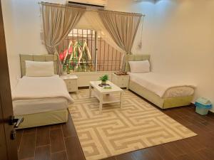 a bedroom with two beds and a window and a table at شاليه لارا in Rayyis
