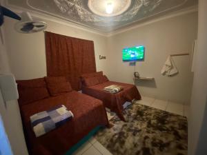 a bedroom with two beds and a tv on the wall at MOMENTS OF JOY GUESTHOUSE in Boksburg