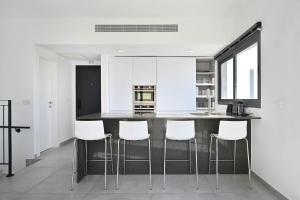 una cucina con armadi bianchi e un bancone nero con sgabelli bianchi di Glamorous 3BR Penthouse near Rothschild Boulevard a Tel Aviv