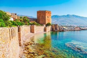 a castle and a wall next to a body of water at Deniz Pansiyon in Alanya