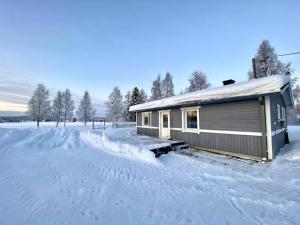 a house is covered in snow in a field at Viihtyisä mökki luonnonhelmassa 