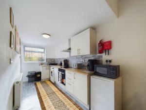 a kitchen with white cabinets and a microwave at Cozy Hull House near City Centre - Walkable to the Deep in Hull
