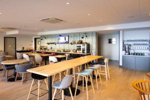 un restaurant avec des tables et des chaises en bois ainsi qu'un bar dans l'établissement Campanile Limoges Centre - Gare, à Limoges