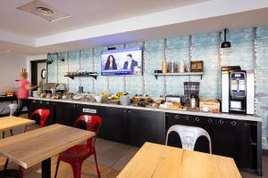 a restaurant with a counter with tables and chairs at Campanile Limoges Centre - Gare in Limoges