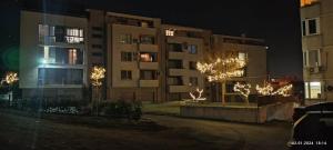 a building at night with christmas lights on trees at Апартамент Туида in Sliven