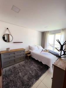 a bedroom with a bed and a dresser and a mirror at Vista inesquecível para o mar homeclub BetoCarrero in Penha
