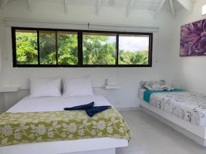 Habitación blanca con 2 camas y ventana en Casa de las Flores tropical, en San Andrés