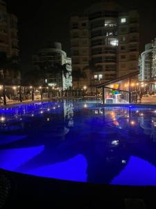 a swimming pool with blue lights in a city at night at Vista inesquecível para o mar homeclub BetoCarrero in Penha