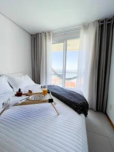 a bedroom with a large white bed with a window at Vista inesquecível para o mar homeclub BetoCarrero in Penha