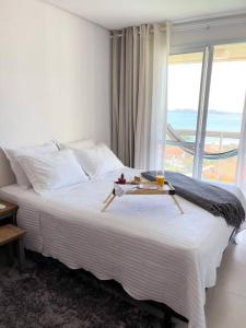 a bedroom with a bed with a view of the ocean at Vista inesquecível para o mar homeclub BetoCarrero in Penha