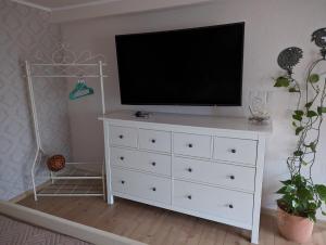 a white dresser with a television on top of it at Casa Hibiscus 2 in Putbus