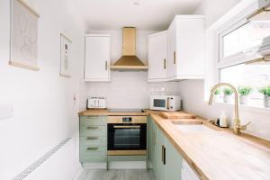 una cucina con armadi verdi e bianchi e un lavandino di Designer 4-Bed Home in the Heart of Belfast a Belfast