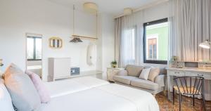 a white bedroom with a bed and a couch and a chair at Bed and Chic in Las Palmas de Gran Canaria