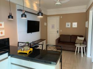 a kitchen and living room with a couch and a television at Ocean Flat Premium com vista para o mar in Vila Velha