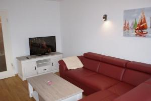 sala de estar con sofá rojo y TV de pantalla plana en Speicherstadt - ABC171 en Wismar