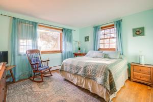 een slaapkamer met een bed, een stoel en ramen bij Cozy Cape Cottage with Private Dock on Bass River in West Dennis
