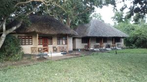 een klein huis met een rieten dak en een tuin bij The Nyerere Selous Ngalawa Tented Camp in Kwangwazi