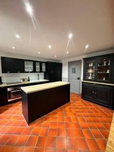 eine Küche mit schwarzen Schränken und orangefarbenem Fliesenboden in der Unterkunft L’ancienne ferme in Sainte-Marie-aux-Mines