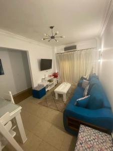 salon z niebieską kanapą i telewizorem w obiekcie شقة مفروشةومريحةفي مدينتي قريبة من كل الخدمات والحركة w mieście Madinaty