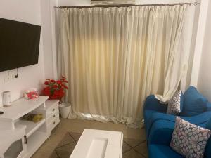 salon z niebieską kanapą i telewizorem w obiekcie شقة مفروشةومريحةفي مدينتي قريبة من كل الخدمات والحركة w mieście Madinaty +11 zdjęć