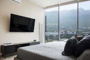 a bedroom with a bed with a flat screen tv on the wall at Lujoso departamento a 5 minutos de San Pedro in Monterrey