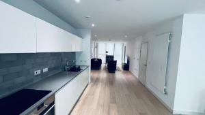 a kitchen with white cabinets and a wooden floor at 2 BED 4 ADULTS IN ROYAL WHARF in London