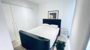 a white bedroom with a bed and a tv at 2 BED 4 ADULTS IN ROYAL WHARF in London