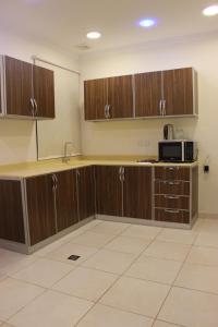 a kitchen with wooden cabinets and a microwave at دانة الشرقية للشقق المخدومة بالدمام Danat Al Sharqiah Serviced Apartments in Dammam