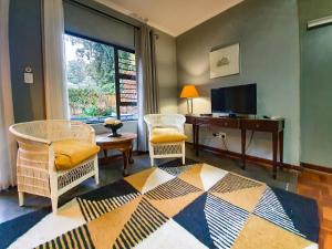 Johannesburg的住宿－The Melville Quarters，一间卧室配有两把椅子、一张桌子和一台电视