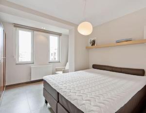 ein Schlafzimmer mit einem großen Bett in einem Zimmer mit Fenstern in der Unterkunft Modern appartement - Zeezicht - Perfecte ligging in Koksijde
