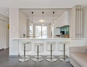 a white kitchen with bar stools and a couch at Modern appartement - Zeezicht - Perfecte ligging in Koksijde