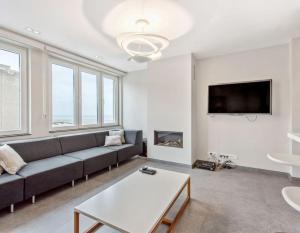 a living room with a couch and a tv at Modern appartement - Zeezicht - Perfecte ligging in Koksijde