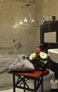ein Badezimmer mit einem Tisch mit Blumen darauf in der Unterkunft Hotel Landhaus Marienstein in Bergen