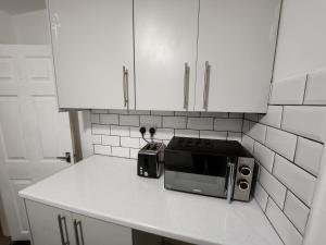 a kitchen counter with a microwave and white cabinets at Goodison Accommodation in Liverpool