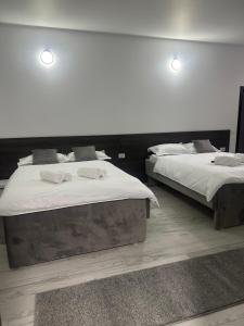 two beds in a bedroom with white sheets and towels at MODERN House in Sighetu Marmaţiei