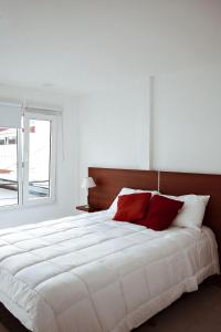 sypialnia z dużym białym łóżkiem z czerwonymi poduszkami w obiekcie Gente del Sur - Antartida w mieście Ushuaia