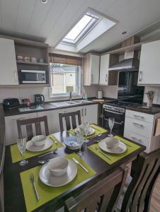 una cocina con una mesa con platos y vasos. en BEAUTIFUL LODGE on SHOREFIELD Country Park on edge of New Forest ENTERTAINMENT AND LEISURE PASSES INCLUDED, en Milford on Sea