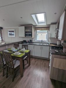 a kitchen with a table with chairs and a sink at BEAUTIFUL LODGE on SHOREFIELD Country Park on edge of New Forest ENTERTAINMENT AND LEISURE PASSES INCLUDED in Milford on Sea