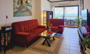 een woonkamer met twee rode banken en een tafel bij Patong Tower Cozy Comfy Luxury Apartment with Seaview, for 1-3 people, in Phuket in Patong Beach