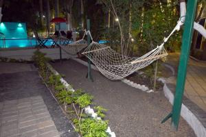 a hammock in a garden next to a pool at The Whispering Palms Resort in Bhopal