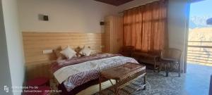 a bedroom with a bed and a table and a window at swayambhu homestay in Joshīmath