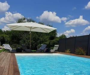 una piscina con sombrilla y sillas y una piscina en The Railway Cottage at Montazels, en Espéraza