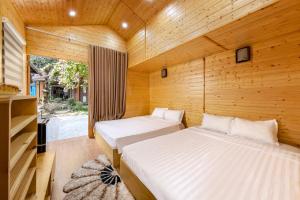 two beds in a wooden room with a window at Tam Coc Friends Bungalow Ninh Bình in Ninh Binh