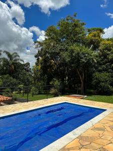 una piscina azul con un árbol en el fondo en Casa de campo Itirapina/SP en Itirapina