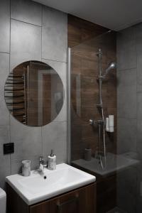 a bathroom with a sink and a shower with a mirror at Gogodz Chalet Resort in Yablunytsya