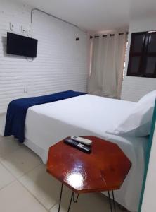 - une chambre avec un lit et une table avec télécommande dans l'établissement Trilha dos Ventos Cumbuco, à Cumbuco