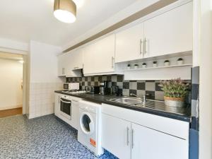ロンドンにあるCS Apartments Hyde Parkのキッチン(白いキャビネット、洗濯機、乾燥機付)
