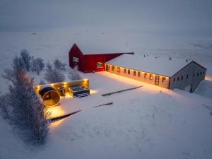 un edificio con luces en la nieve junto a un granero en Tindasel Lodge, en Hella